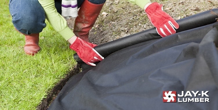 Image of person laying down landscaping fabric